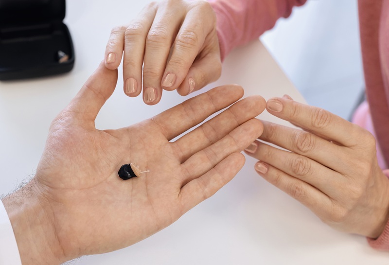 Audiologist provides a modern in-the-ear hearing aid for improved hearing in hearing room