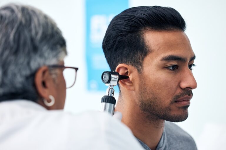 Ear check, man and clinic doctor with patient consultation for hearing and wellness at hospital.