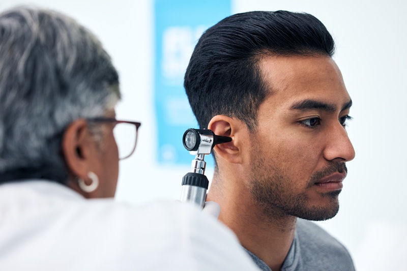 Ear check, man and clinic doctor with patient consultation for hearing and wellness at hospital.