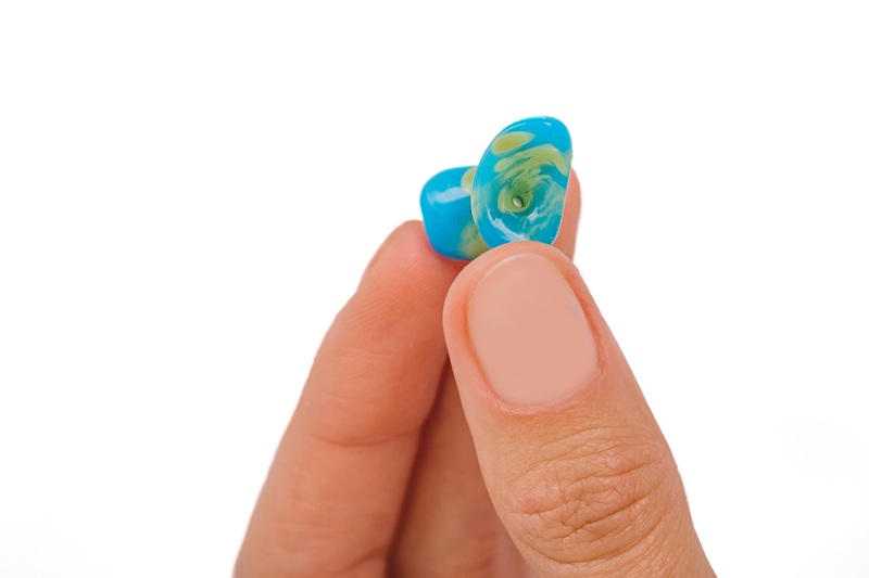 Isolated on white earplug in female hand. Personally molded earplugs close-up. Part of the set