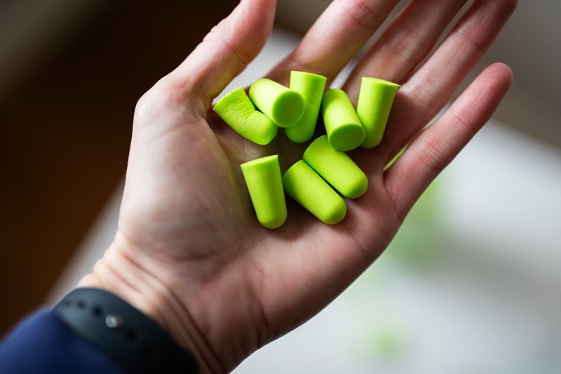 a hand with green earplugs