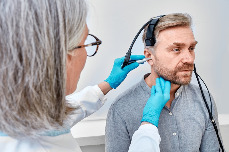 Handsome man during tympanometry or impedance audiometry and test of middle-ear function with audiologist using tympanometer probe at hearing clinic