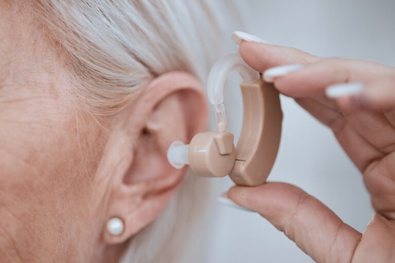 Hand, closeup and hearing aid in ear for old woman, audio or sound for listening, healthcare or ret.