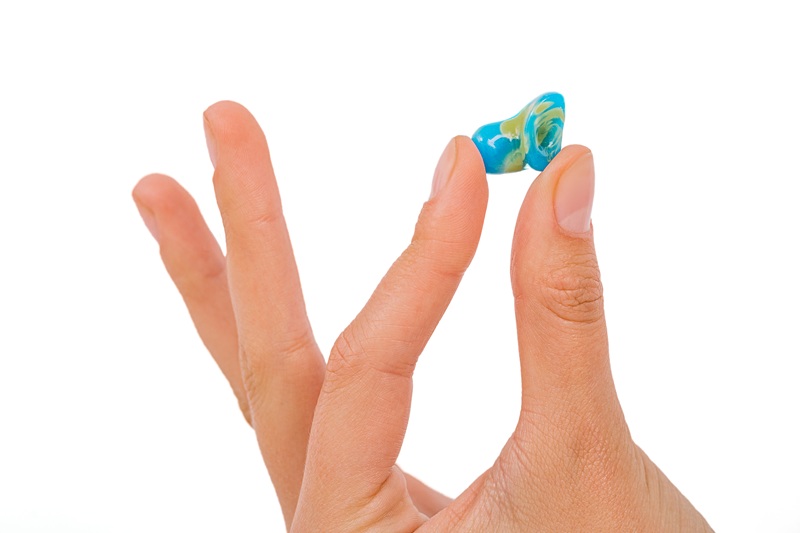 Isolated on white earplug in female hand. Personally molded earplugs close-up. Part of the set