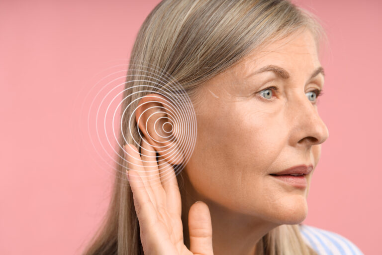 Mature woman cupping her hand behind her ear to hear better, with sound wave graphic, illustrating hearing loss from otosclerosis